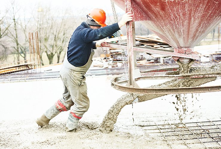 Worker during concrete pouring into formwork