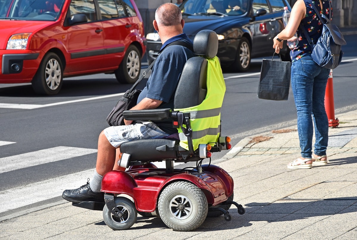 Pwd on a electric wheelchair at the sidewalk